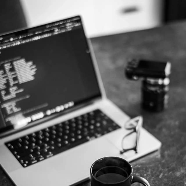 Scrivania monocromatica con laptop, tazza e accessori da lavoro.
